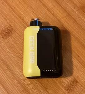 Click to view full screen Yellow and black Geek Bar device on a wooden table