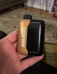 Click to view full screen Gold and black Geek Bar device held in a hand
