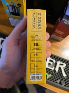 Click to view full screen Hand holding a yellow VOOPOO VRIZZ 2 product box with specifications on the side